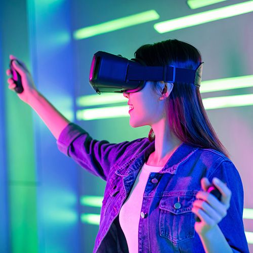 Eine Frau mitsamt 3D-Datenbrille steht vor einem bunten Hintergrund.