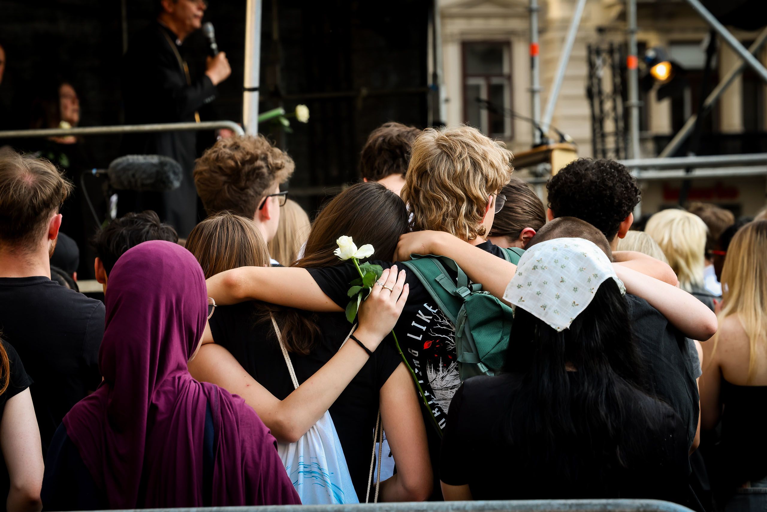 Junge Menschen, von hinten fotografiert, trauern gemeinsam am Grazer Hauptplatz. Ein Mädchen hält eine weiße Rose.
