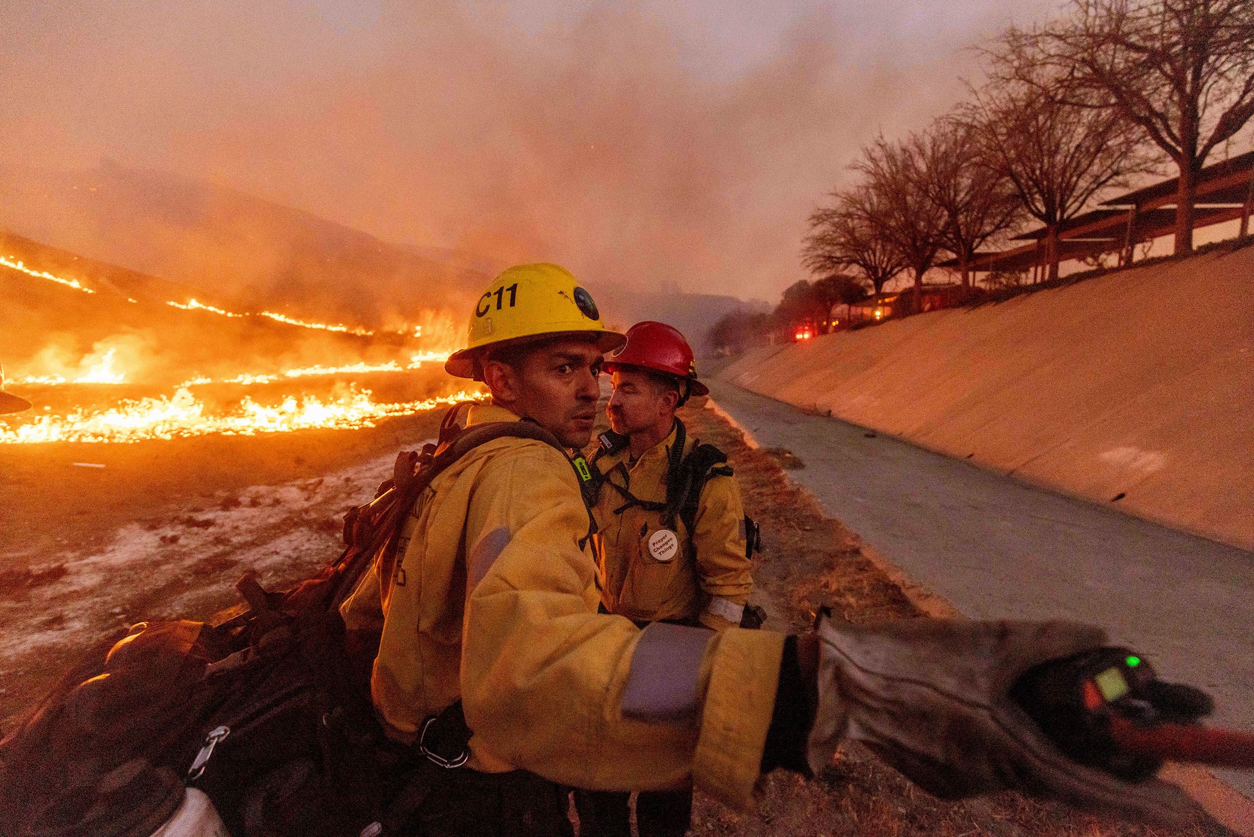 Feuerwehrmänner vor brennendem Boden im West-Hills-Viertel von Los Angeles