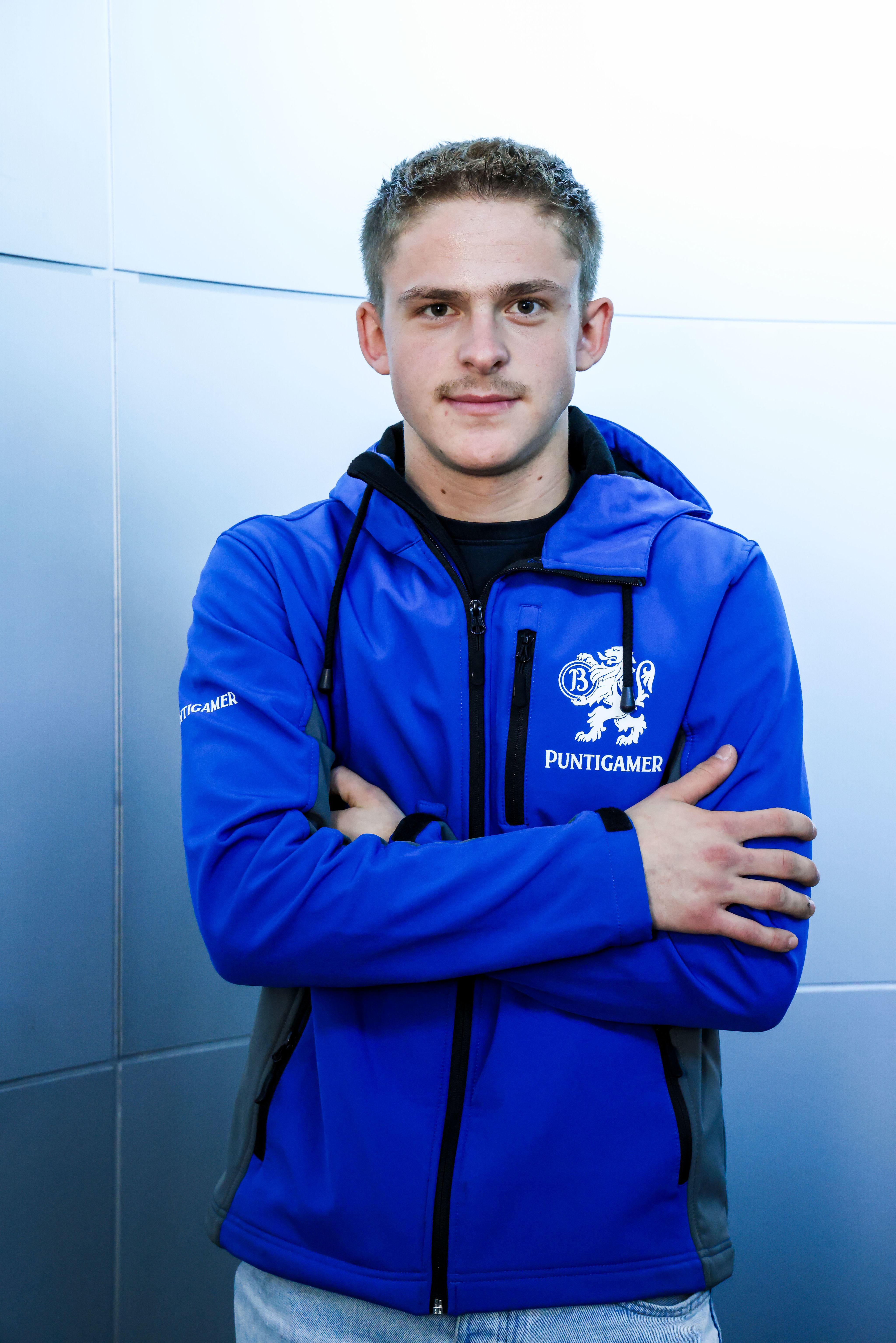 Der Lehrling trägt eine blaue Weste mit der Aufschrift "Puntigamer" und posiert für das Foto.