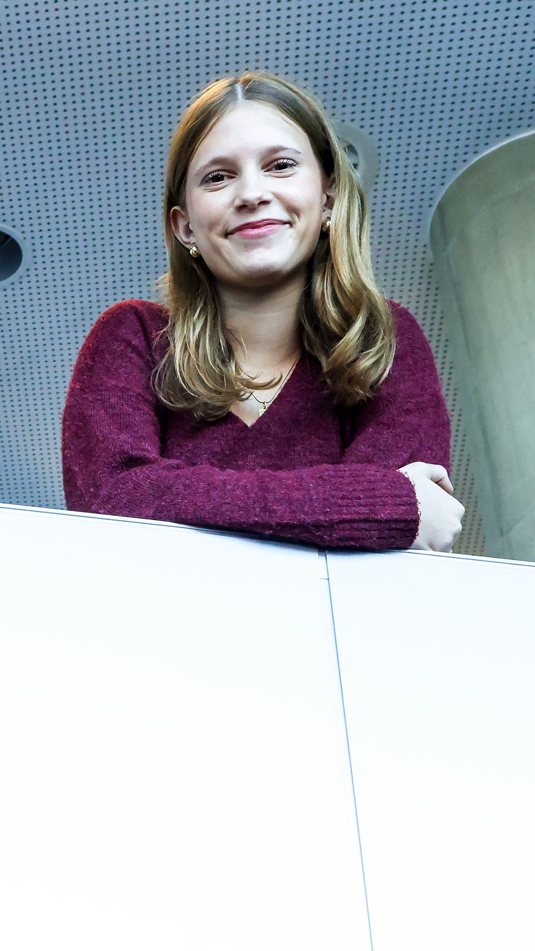 Die Schülerin trägt ein lila T-Shirt und posiert für das Foto, auf ihre Unterarme gestützt.