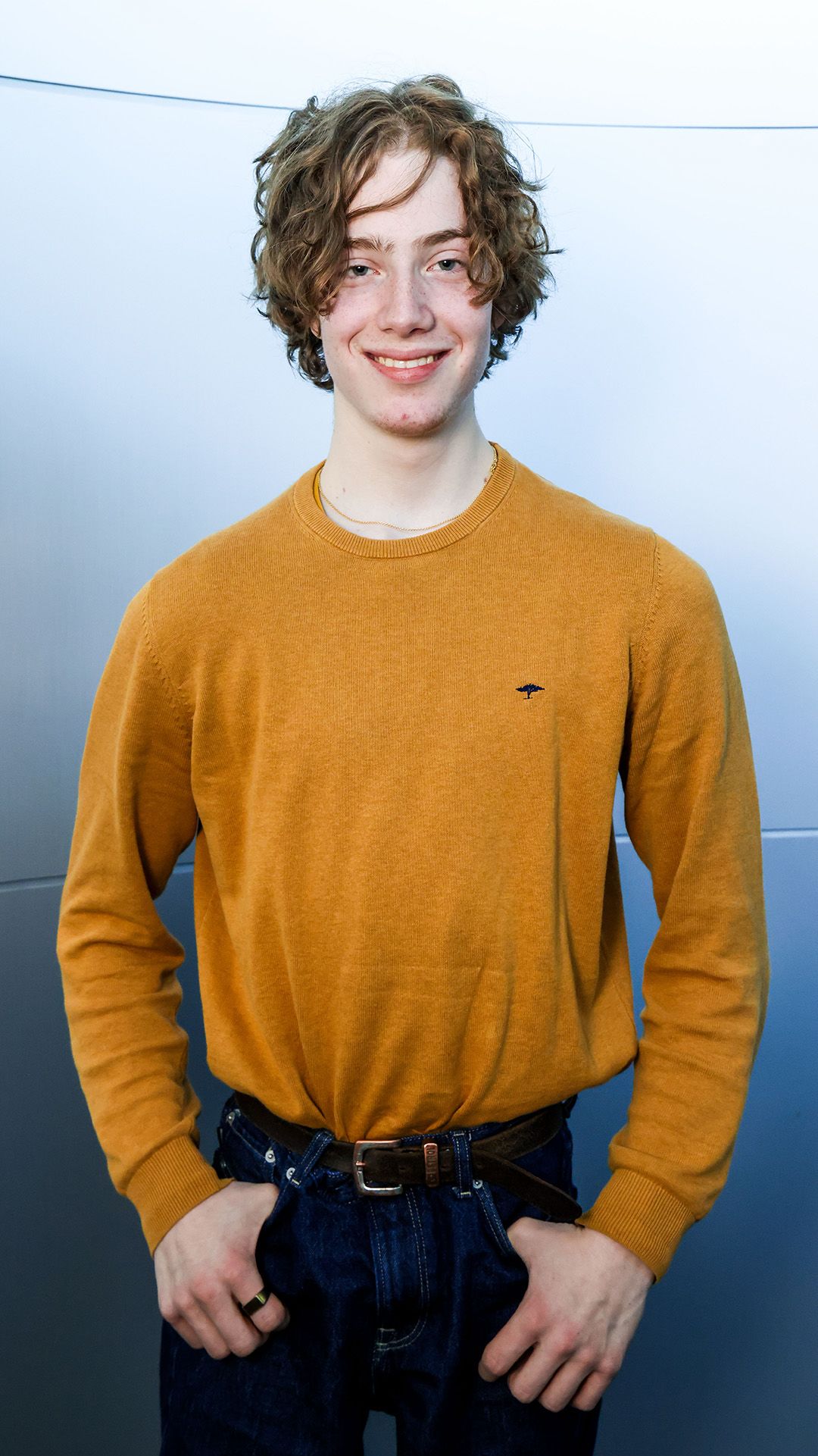 Der Schüler trägt ein gelbes T-Shirt und posiert für das Foto.