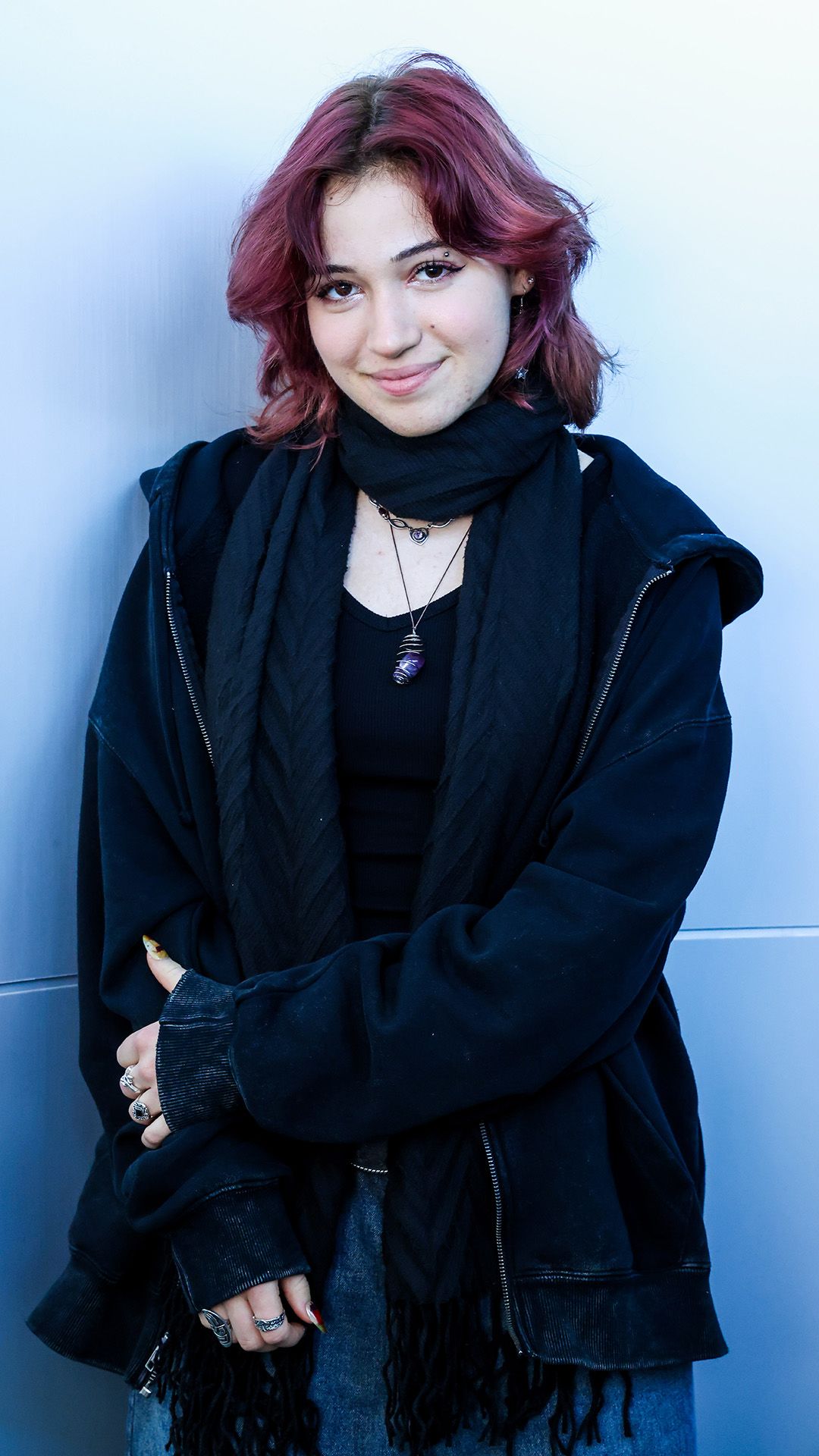 Die Schülerin trägt ein schwarzes T-Shirt und eine dunkle Weste und posiert für das Foto.