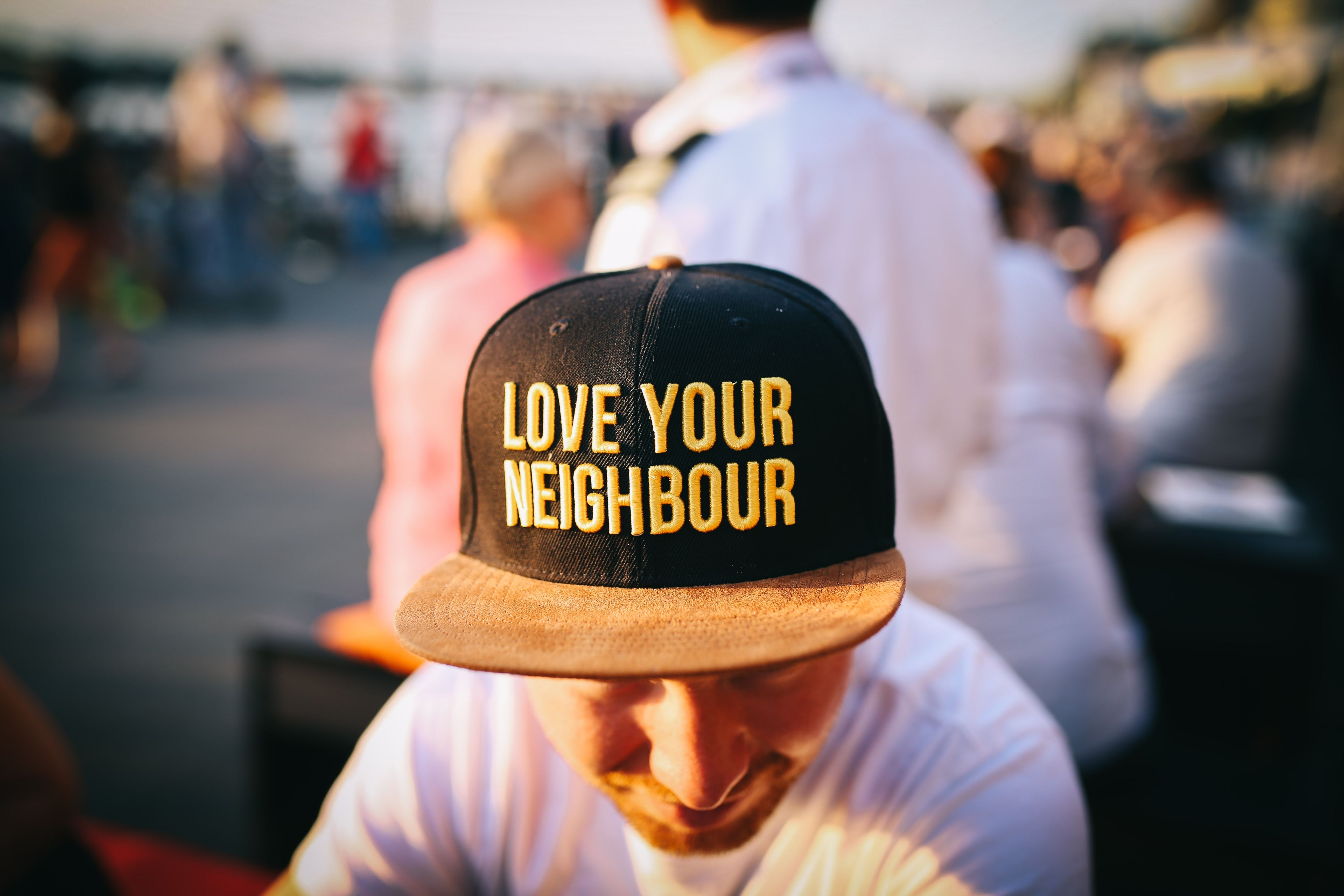 Person mit schwarzer Kappe, die den gelben Schriftzug "Love your Neighbour" trägt.
