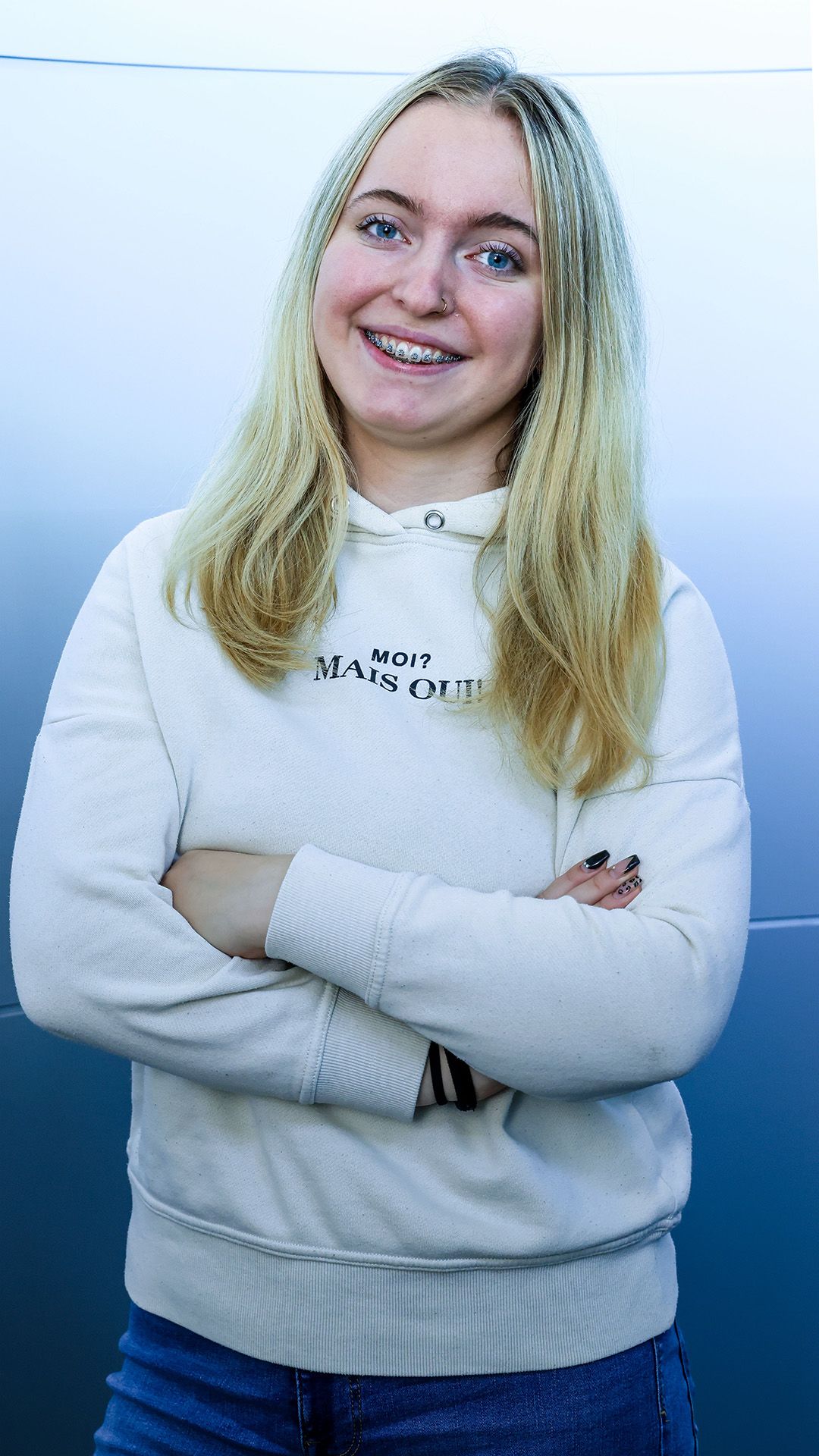 Der weibliche Lehrling trägt einen weißen Pullover und posiert für das Foto.